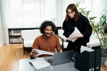 Girl and guy collaborating on a project, with laptop and notes