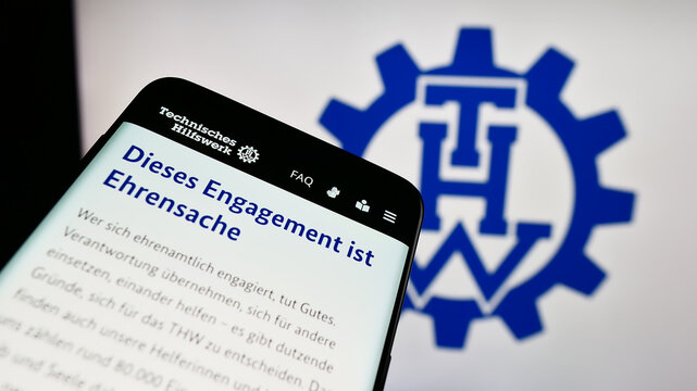 Stuttgart, Germany - 10-08-2023: Smartphone with webpage of organization Bundesanstalt Technisches Hilfswerk (THW) in front of logo. Focus on top-left of phone display.