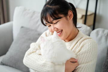 Happy Woman Playing with Cat in Cozy Living Room at Home.