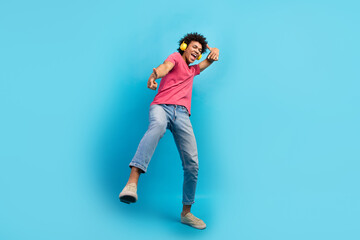 Full size photo of attractive young man dancing headphones fingers point you wear trendy pink clothes isolated on blue color background