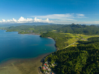 Tropical landscape of coastline with small village and blue sea. Skyscape. Mindanao, Philippines.