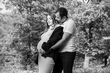 Handsome young men are together, the wife is pregnant, walking in nature. Black and white image.