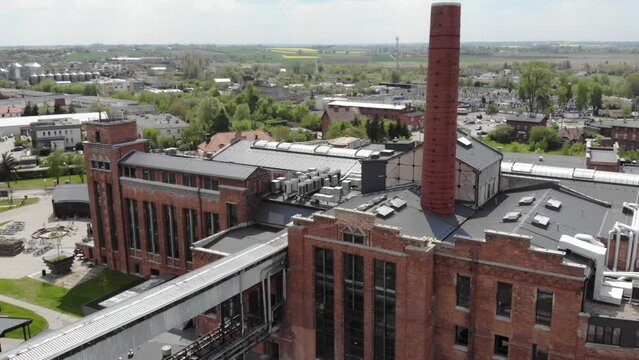 the chimney in Arche Hotel Żnin inside old sugar factory in Poland. The tall chimney of the factory is a famous landmark, rising above the surrounding landscape. Aerial orbit tilt-down shot .