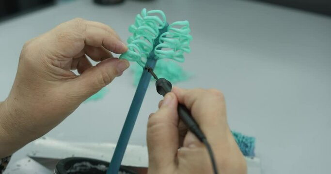 Woman with soldering iron attaches plastic parts at the factory