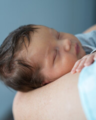 Baby's head in mother's hands. Mom holds a newborn boy, the baby sleeps sweetly. Infant health and development. The birth of a child and the love of parents