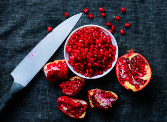 Pomegranate seeds and knife on a black background. Toned.