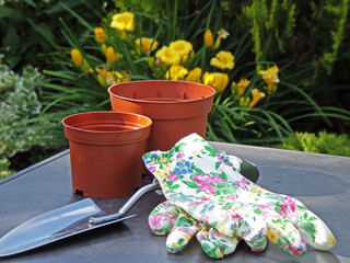 BHP w ogrodzie, rękawiczki ogrodowei, metalowa łopatka i doniczki na stole, Gardening tools, safe...
