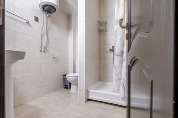 toilet and detail of a corner shower cabin with wall mount shower attachment