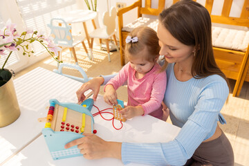 Mother and daughter playing with wooden cash register toy - obrazy, fototapety, plakaty