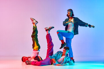 Funny young men in stylish colorful vintage sportswear doing aerobics exercises against gradient...