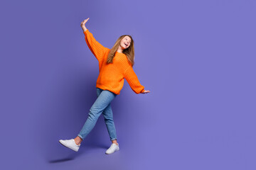 Full length photo of dreamy excited teenager girl orange sweater with jeans flying arms look...