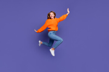 Fototapeta na wymiar Full length photo of running jumper teen girl flying with hands like wings carefree spending weekend isolated on purple color background