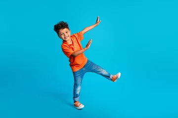 Fotobehang Full body size photo of dance cool little boy showing his arms dab carefree weekend positive mood disco isolated on blue color background © deagreez