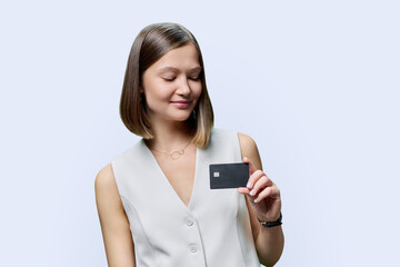 Young woman bank employee showing credit card, on white background