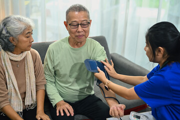 Obraz premium Health visitor measuring blood pressure senior man at home. Elderly healthcare concept