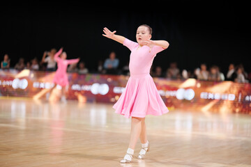 Dancer, a beautiful athlete in a pale pink dress against the background of the stage. Sports and ballroom dancing