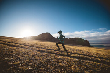 Woman trail runner cross country running in lakeside mountains