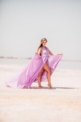 Woman pink salt lake. Against the backdrop of a pink salt lake, a woman in a long pink dress takes...