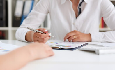 Businesswoman holding a silvery pen in her hand indicates the interlocutor for a diagram on the form. Of annual report on the financing of organizations trains the processing of this statistical study