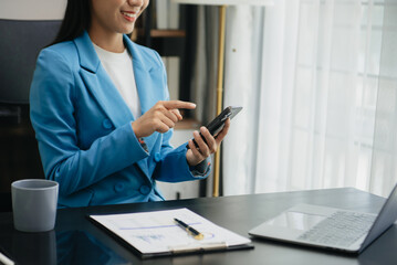 Young beautiful woman typing on tablet and laptop while sitting at the working white table modern office.