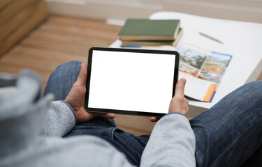 Male hand holds tablet pad in home setting while sitting on the couch engaged an internet. Surfing using application to press a finger on the display leisure listering music concept closeup. - obrazy, fototapety, plakaty