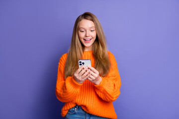 Photo of excited teen girl browsing brand new iphone 15 check for modern features last release device isolated on violet color background