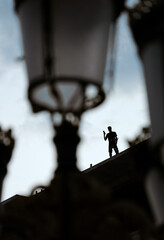 Silhouette of a man standing on a rooftop in Skopje taking photos with his mobile - obrazy, fototapety, plakaty