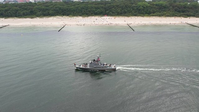 Naval ship is sailing at sea, aerial view. A gray navy ship operating on a calm sea. Maritime military fleet
