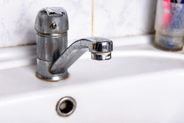 Dirty faucet with limescale, calcified water tap in sink.