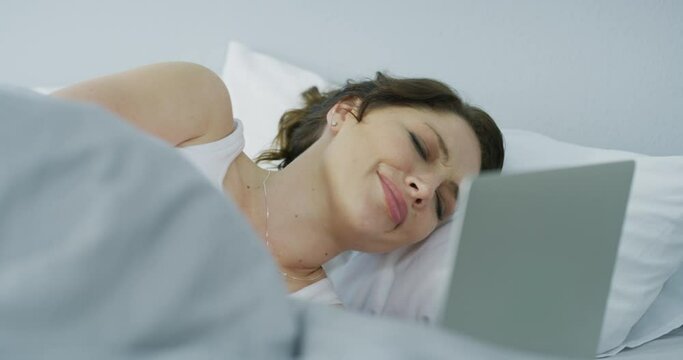 Woman, laptop and pain of stomach in bedroom for gut health, indigestion and gastric virus at home. Stress, menstruation and ibs at computer in bed with constipation, anxiety and endometriosis crisis