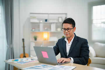 Fototapeta na wymiar Smart Asian businessman with suit smiling wearing glasses working with computer laptop. concept work form home. Freelance life style, New normal social distancing lifestyle. Work form anywhere concept