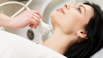 A doctor diagnoses a patient's thyroid gland using an ultrasound scanner. A woman holds an...
