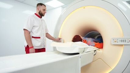 A doctor performs an MRI on a patient in the clinic. The girl lies in an MRI machine. Magnetic...