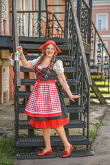 Fantasy portrait Ukrainian happy girl looks at camera. Authentic woman holds sunflower. Long hair flying in wind waving. Art photo levitation. National ethnic black dress. Wreath red crown flowers