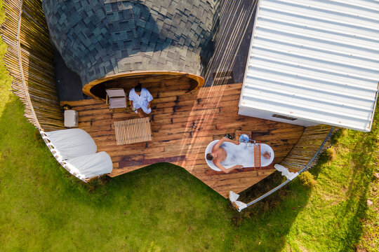 a couple of men and women camping in the mountains of Northern Thailand during vacation. Outdoor bathroom, and bathtub during sunset in the mountains at an igloo hut
