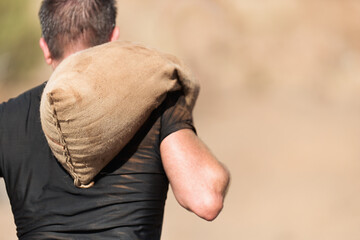 Mud race runners, young man carrying tear sandbag