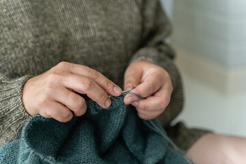 Close up of the woman's hand knitting the cozy sweater for a Christmas. Happiness and creative job