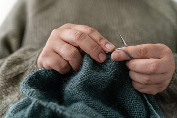 Close up of the woman's hand knitting the cozy sweater for a Christmas. Happiness and creative job