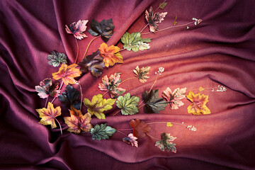Flower arrangement of Gerhera leaves on a burgundy-brown background.