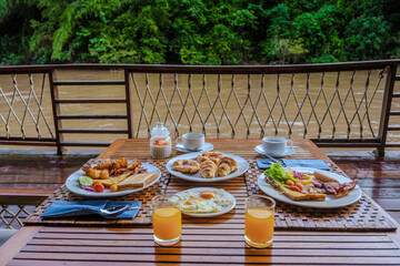 breakfast table at a tropical beach house on the River Kwai in Thailand.Wooden floating raft house in river Kwai Kanchanaburi, Thailand, breakfast with eggs bread and coffee