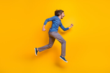 Fototapeta na wymiar Full length photo of impressed funky guy dressed blue pullover hurrying running jumping high isolated yellow color background