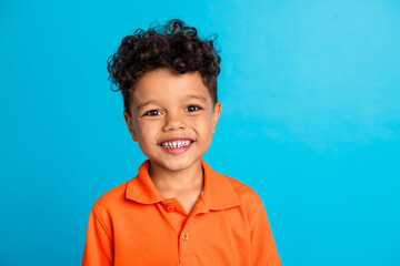 Portrait of positive cheerful kid boy smiling on camera isolated over blue color background