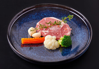 Raw Striploin Steak with vegetable (Broccoli, cauliflower, garlic) top with Himalayan salt and thyme leaves on plate isolated on black background. Prepare beef and vegetables for cooking.