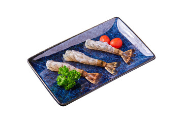 Fresh tiger prawn with parsley leaves and tomato on a plate isolated on white background. Preparing fresh shrimp and ingredients for cooking.