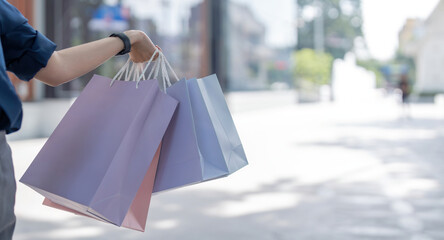 Close up of woman hand holding shopping bags while walking near mall