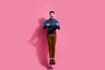 Full length photo of carefree handsome guy using car driving simulation app using steering wheel in air isolated on pink color background