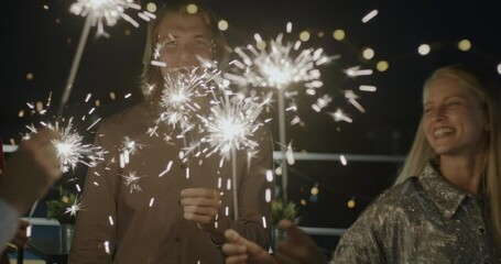 Group of men and women dancing with bengal lights enjoying night party laughing having fun together. Illumination and holidays concept.