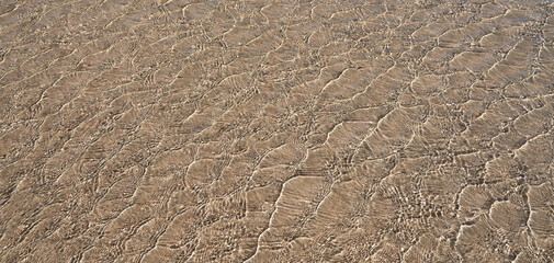 Abstraktes Muster in flachem klarem Wasser über braunem Sand an einem Strand, verursacht durch leichten Wind - Fuerteventura, Kanarische Inseln - obrazy, fototapety, plakaty