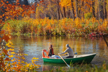 A couple, man and woman sitting in a rowing boat on the water on an autumn day.