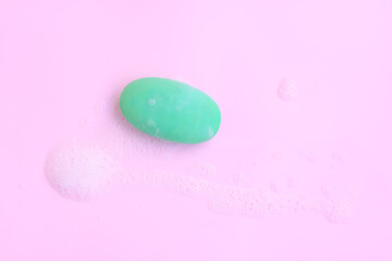Green soap bar with soap foam on pink background, Soap and bubble, Top view